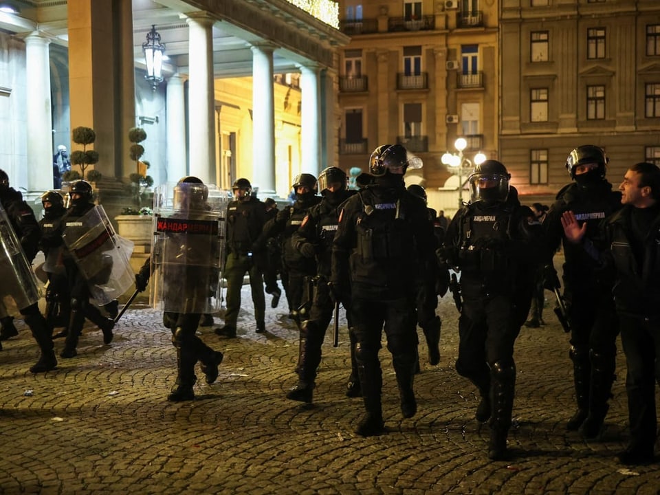 Police forces in full gear walk past Belgrade City Hall.