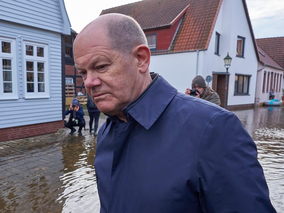 SCholz stands with his shoes in the flooded Verden.