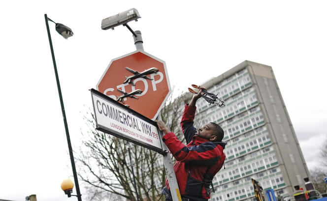 A man removes a Banksy artwork, which shows what looks like three drones on a traffic stop sign, which was unveiled at the intersection of Southampton Way and Commercial Way in Peckham, South East from London, December 22, 2023. 