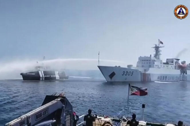 This image from video footage released by the Philippine Coast Guard on December 9, 2023, shows a Chinese Coast Guard vessel (right) using a water cannon on a Philippine boat near Scarborough Shoal at sea from southern China.