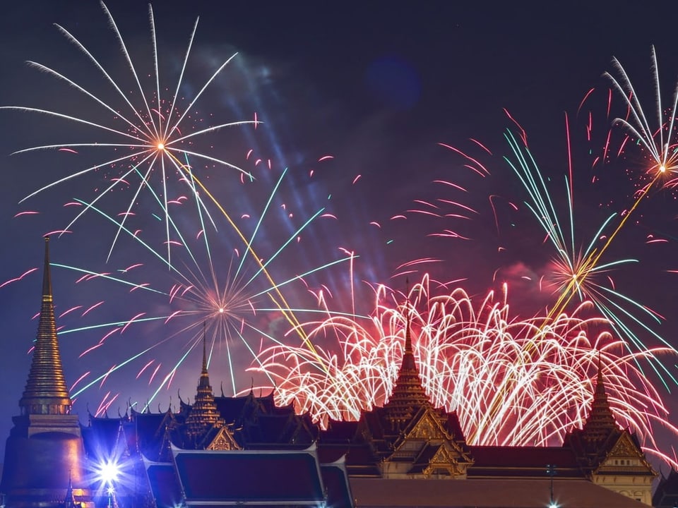 Fireworks explode over the rooftops of the palace.