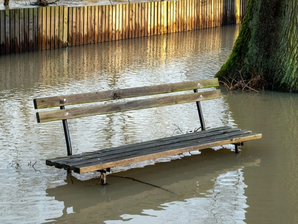 A park bench is almost under water.