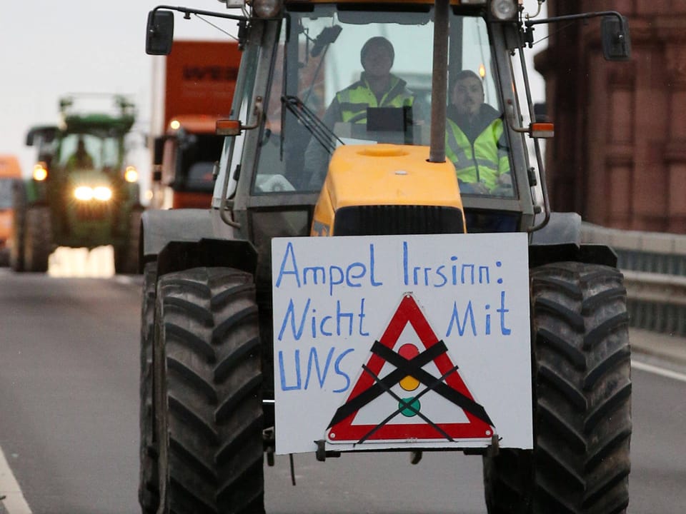A tractor carries a sign that reads “Traffic light madness: not with us!”