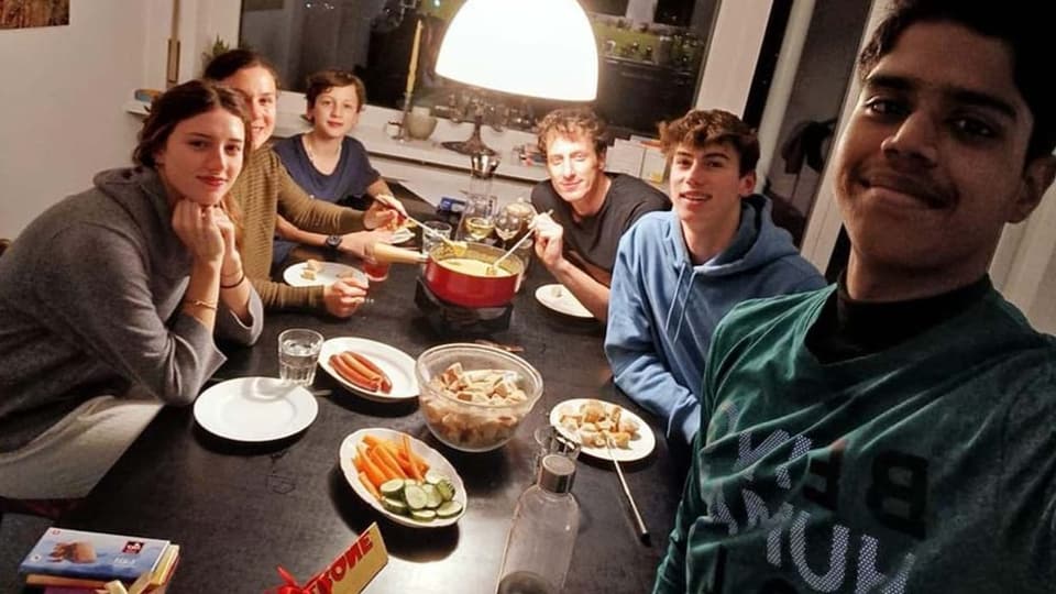 A family and an Indian exchange student eat fondue and Toblerone. 