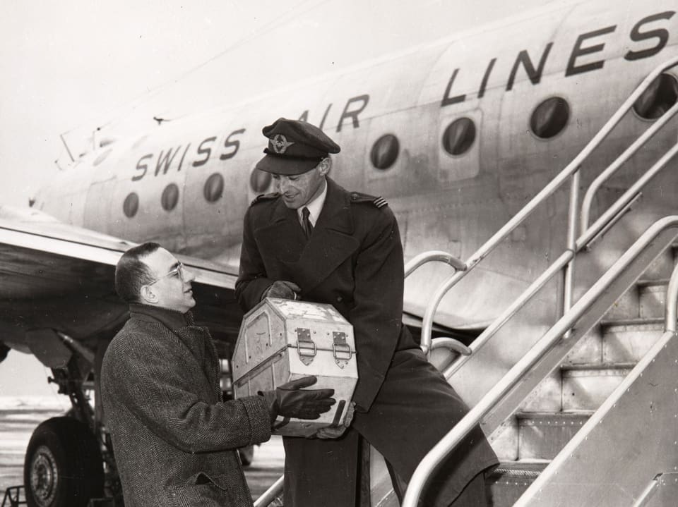 Transporting film rolls in front of a Swissair plane in 1945.