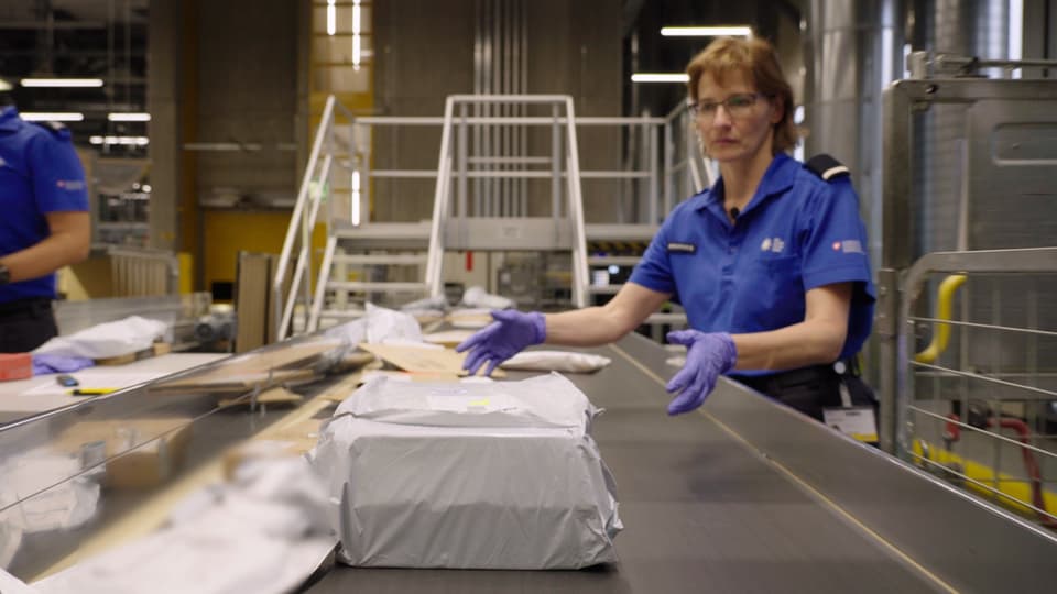 A customs officer takes a package off the assembly line