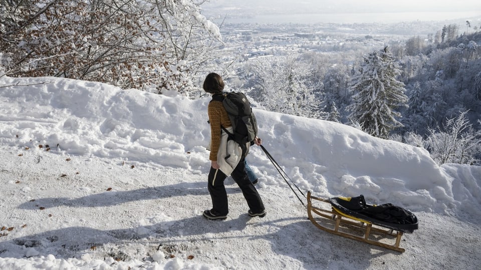 A woman pulls a Davos sledge up a winter path.