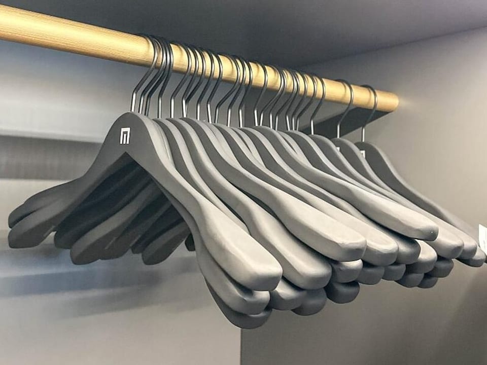 Black clothes hangers hang in a closet
