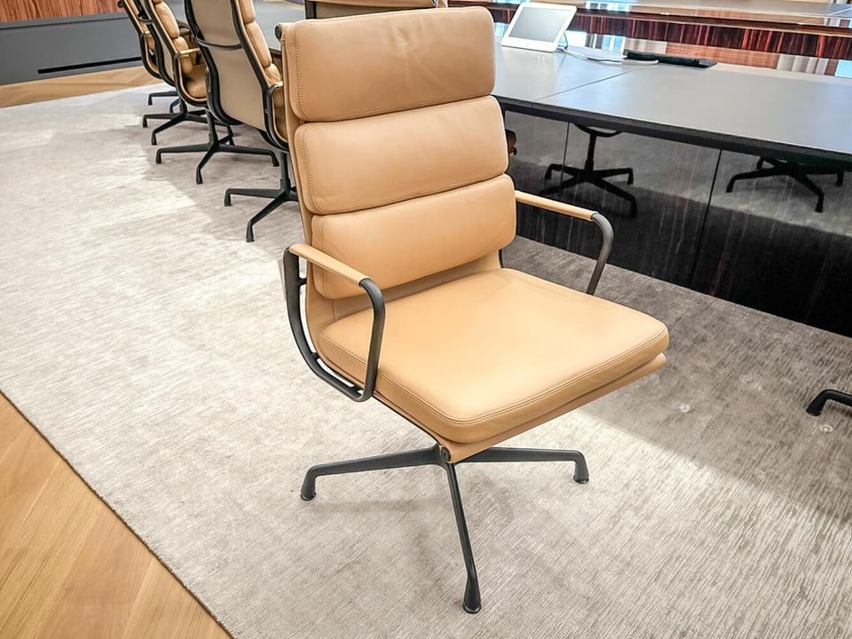A beige leather chair stands on a light gray carpet