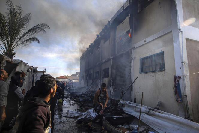 Palestinians try to put out a fire at an UNRWA building that displaced people are using as shelter, after being targeted by Israeli tanks in Khan Younes, southern Gaza Strip, January 24, 2024 . 