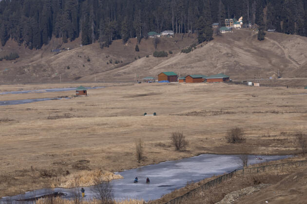 People rest on a frozen pond in Gulmarg, west of Srinagar (Jammu and Kashmir), January 13, 2024.