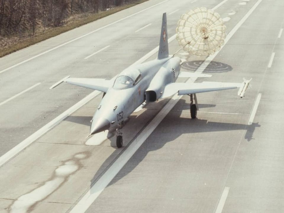 Military jet with drag parachute on highway 