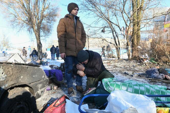Two men stand next to the body of their loved one, lying on the ground, killed following a missile strike in Donetsk, occupied Ukraine, January 21, 2024.