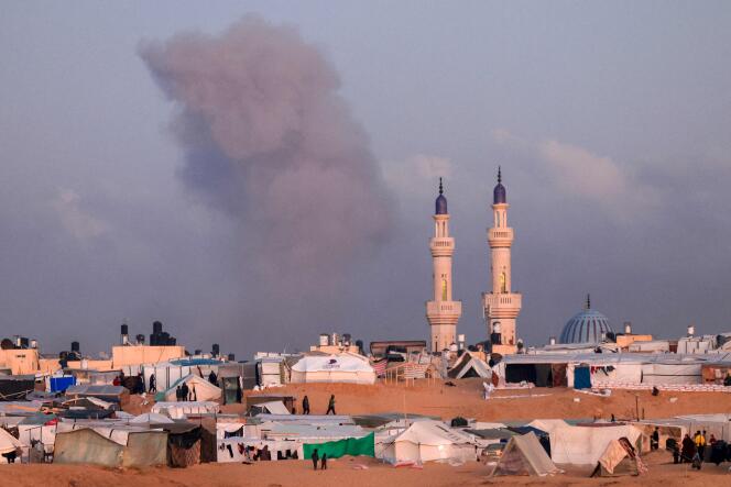 A photo taken at a makeshift camp for displaced Palestinians west of Rafah, near the Egyptian border, shows smoke in Khan Yunis after an Israeli bombardment, January 14, 2024.