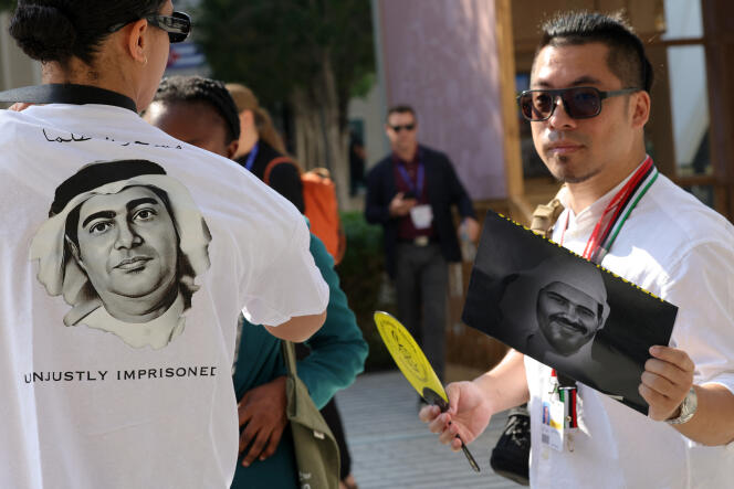 An Amnesty International activist wearing a T-shirt bearing the image of Emirati human rights activist Ahmed Mansoor while another holds a portrait of democracy advocate Mohammed al-Siddiq, during a demonstration to demand their release, in Dubai on December 9, 2023. 