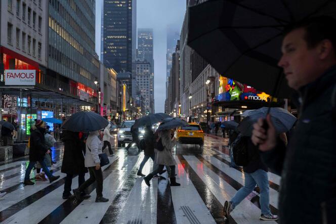 People with umbrellas walk in pouring rain in New York, January 9, 2024.
