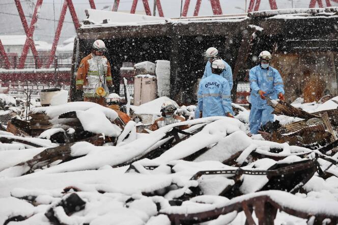 Firefighters search for missing people in the charred ruins of Wajima market as snow covers part of the disaster zone, January 8, 2024, a week after the earthquake.