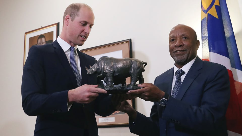 Two men with a small rhino statue