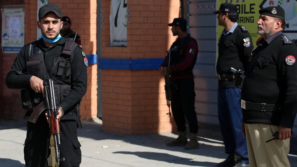 Pakistani security officers stand guard outside a polling station in Peshawar.