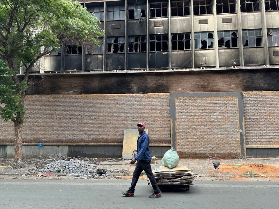 A man walks past a burned-out building