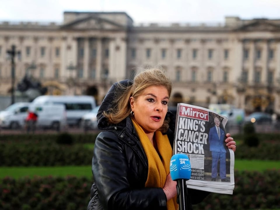 A journalist holds a newspaper in her hand in front of Buckingham Palace.  The title page reads: “King's Cen