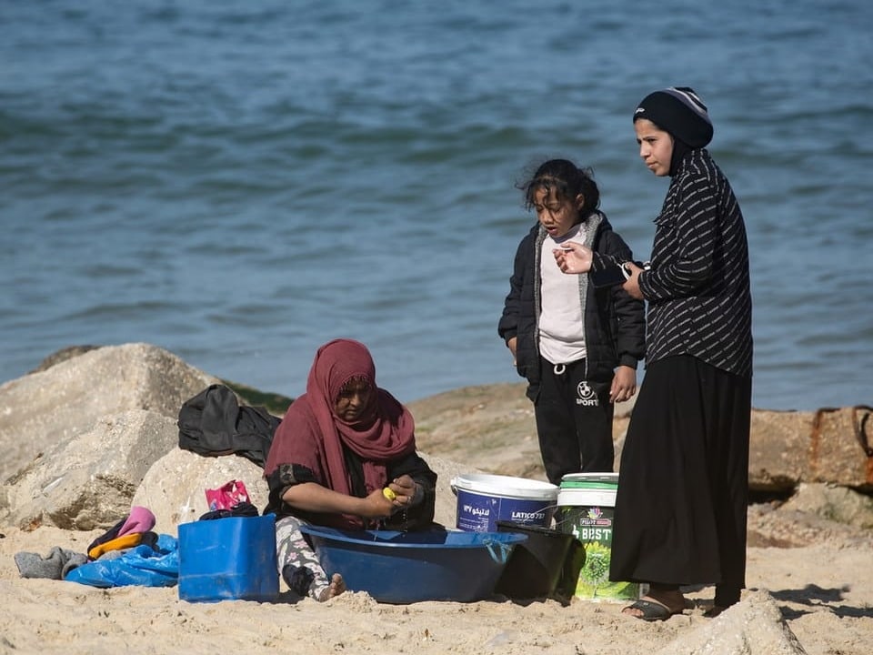A family on the beach washes clothes