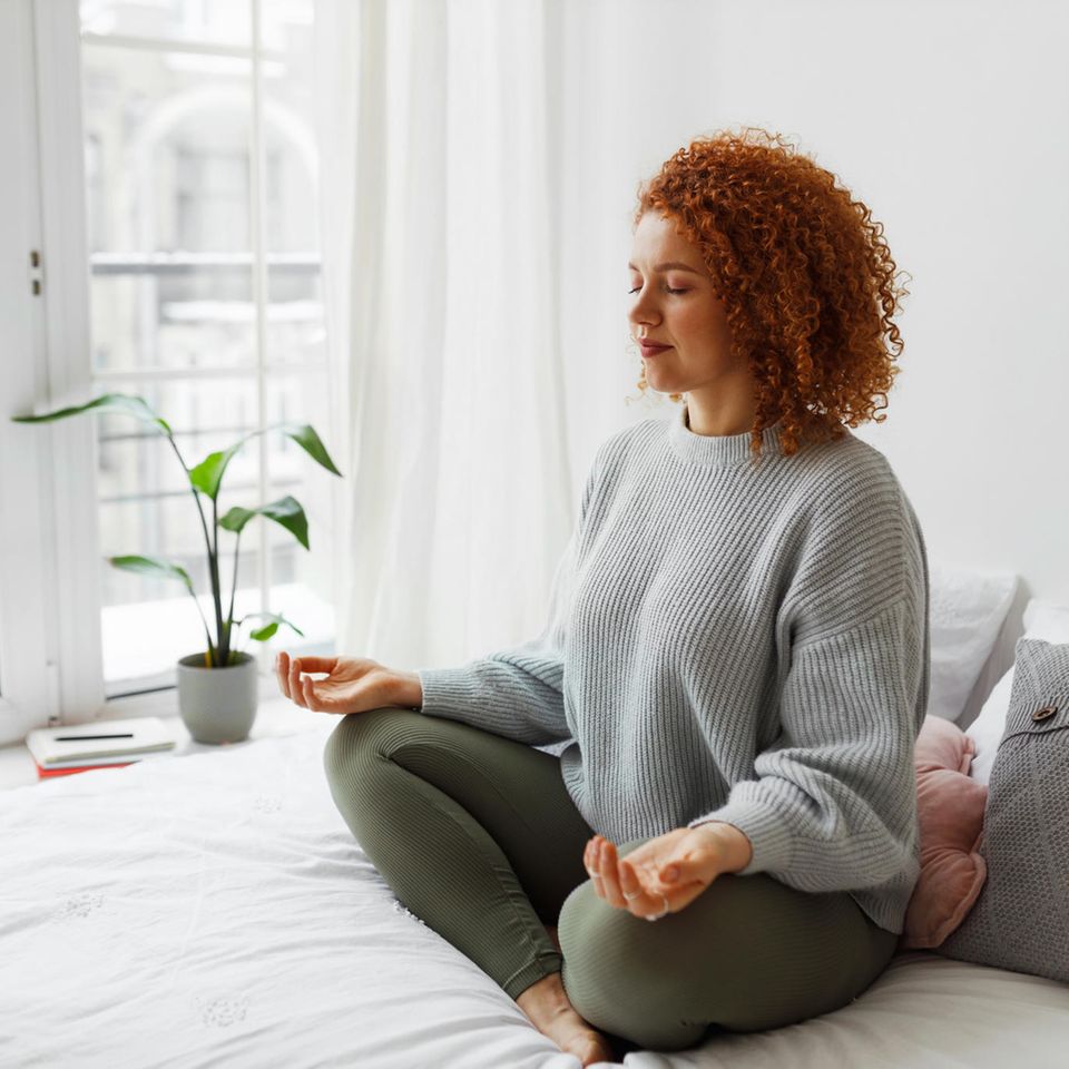 Mindful woman sitting on the bed: How to escape the thought carousel with the 5-4-3-2-1 method