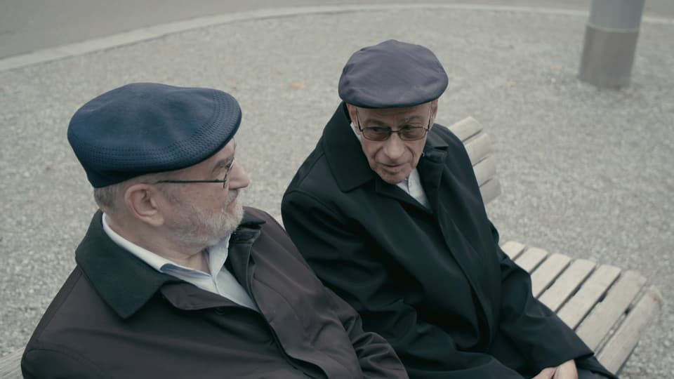 Two older men sit on a park bench