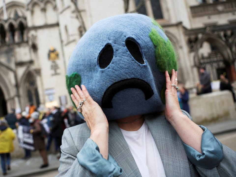 A person with a crying mask representing the earth.