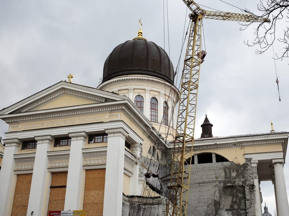 A cathedral with a domed roof, next to a yellow crane.