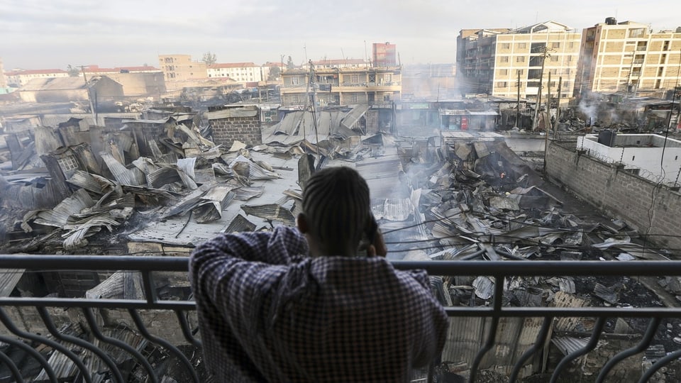 Person on terrace looks at rubble of buildings