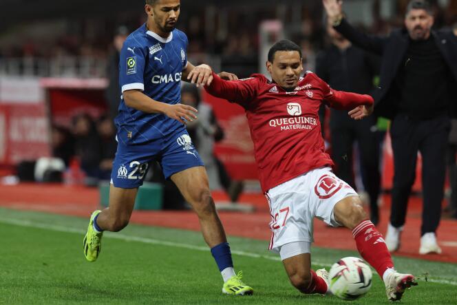 Brest's Kenny Lala (red jersey) tackles the ball in front of Marseillais' Iliman Ndiaye, in Brest, February 18, 2023.