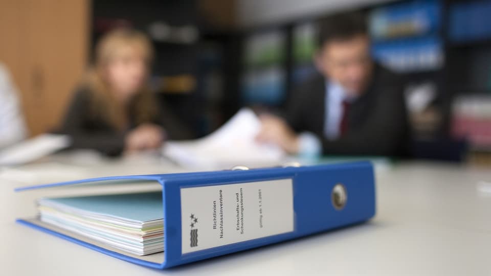Folders on the table, people in the background, at the financial administration of the canton of Aargau