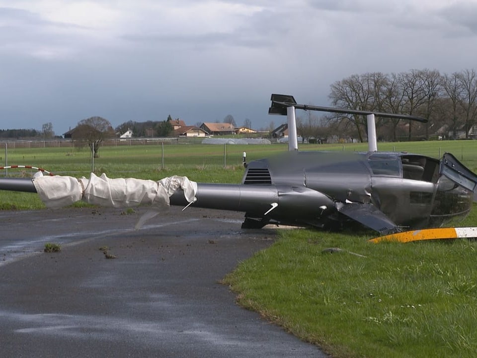 Upturned helicopter, lying on the meadow, wrapped in white at the back.