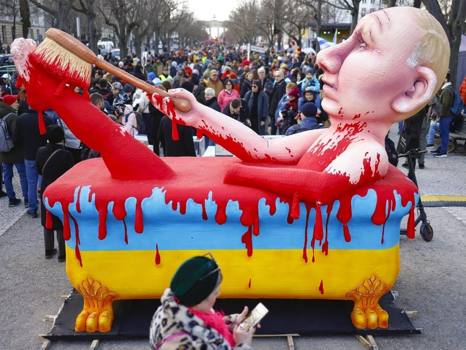Oversized Putin cardboard figure in a bathtub painted with Ukrainian colors and red blood
