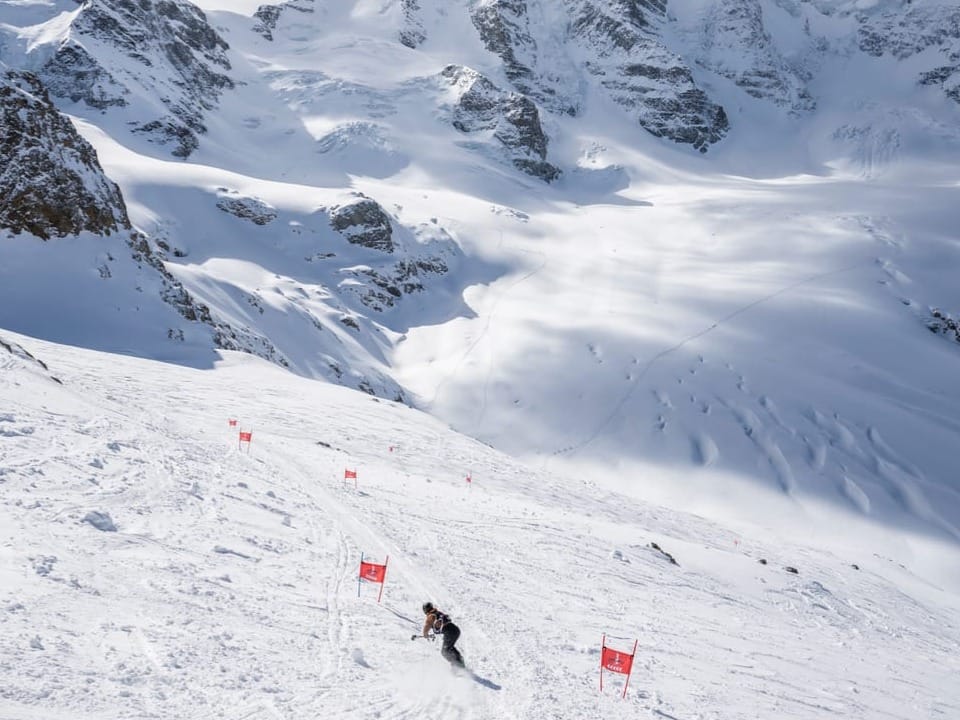 Nevin Galmarini on the glacier descent of the “Diavolezza Glacier Race” with a snowboard and a stick.