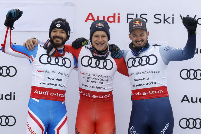 Switzerland's Marco Odermatt, center, celebrates on the podium his victory in the downhill discipline of the Alpine Skiing World Cup, with France's Cyprien Sarrazin, second, left, and Italy's Dominik Paris, third, right , in Saalbach, Austria, on Sunday March 24, 2024