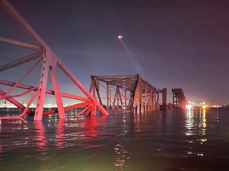 Red shimmering bridge parts in the water at night.