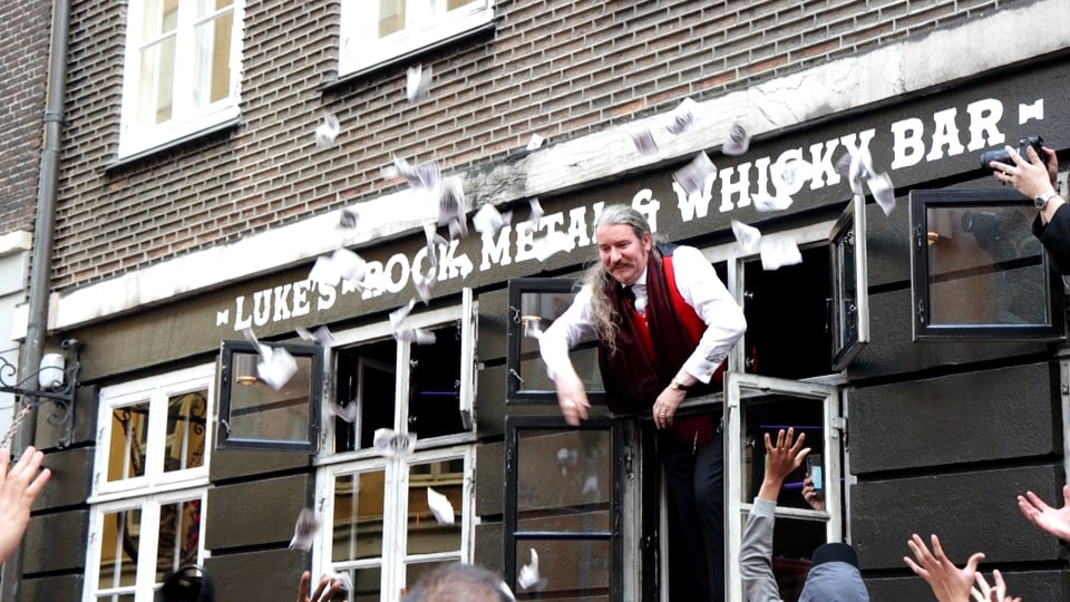 Man throws money out of window of a bar in Copenhagen Old Town