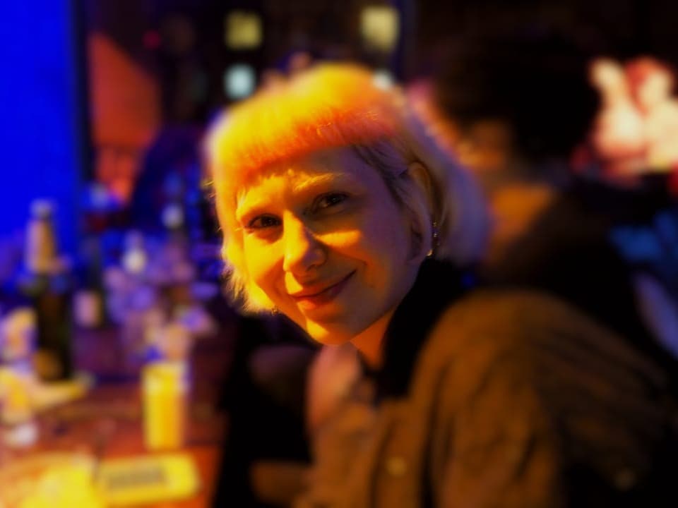 Junge Frau mit blonder Pony-Frisur in einer Bar.