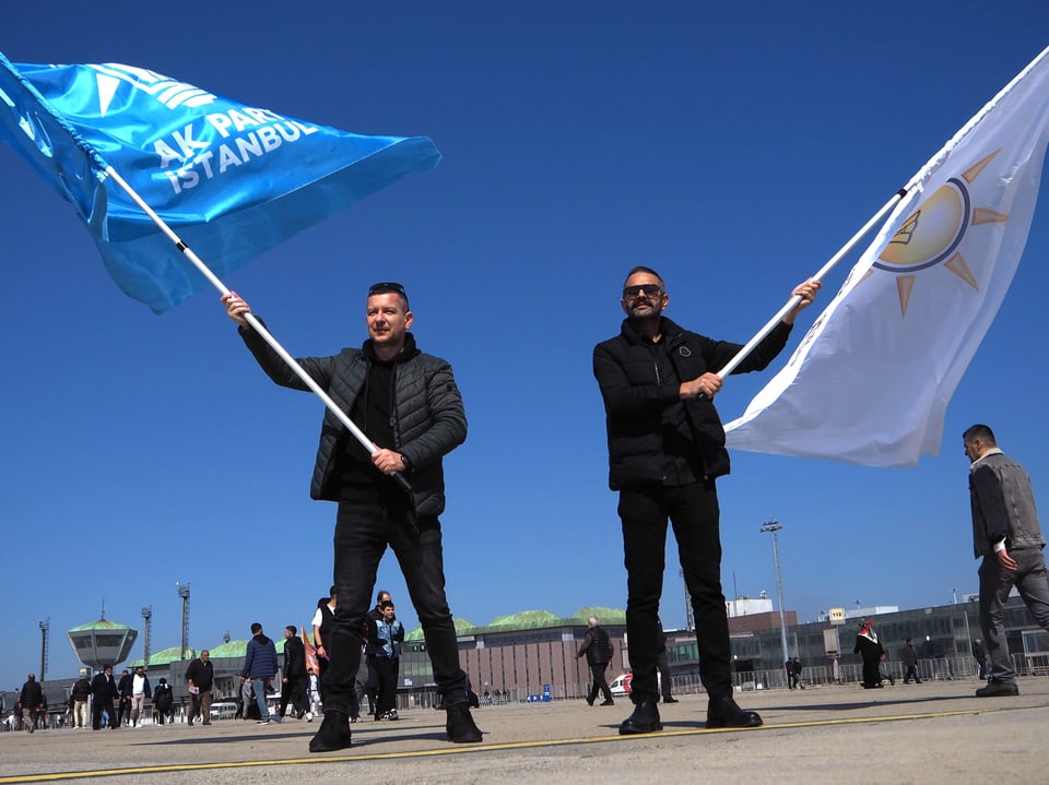 Zwei Männer mit grossen AKP-Flaggen auf der Rollbahn des alten Flughafens.