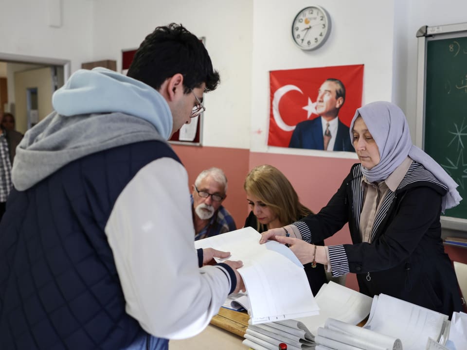 A man collects voting documents at a polling station in Istanbul.  A woman hands it to him.