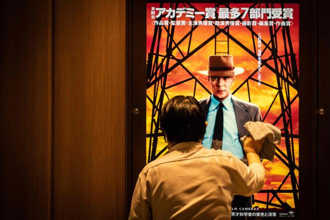 A worker cleans a screen showing an advertisement for “Oppenheimer” in Tokyo, March 29, 2024, the day the film is released in Japanese theaters.
