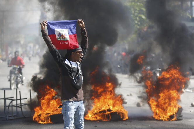 A protester waves a Haitian flag during protests calling for the resignation of Prime Minister Ariel Henry in Port-au-Prince on March 1, 2024.