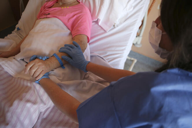 A nurse holds the hand of a patient in the palliative care unit of Eugénie hospital in Ajaccio (Corsica), April 23, 2020.