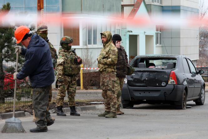 Volunteers from a self-defense unit near a car damaged following an air attack, in Belgorod, Russia, March 22, 2024.