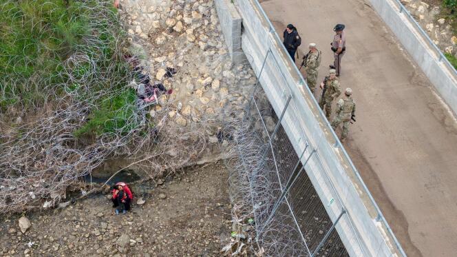 U.S. soldiers and law enforcement officers on a bridge above a group of immigrants who crossed the Rio Grande into the United States, in Eagle Pass, Texas, March 18, 2024 .