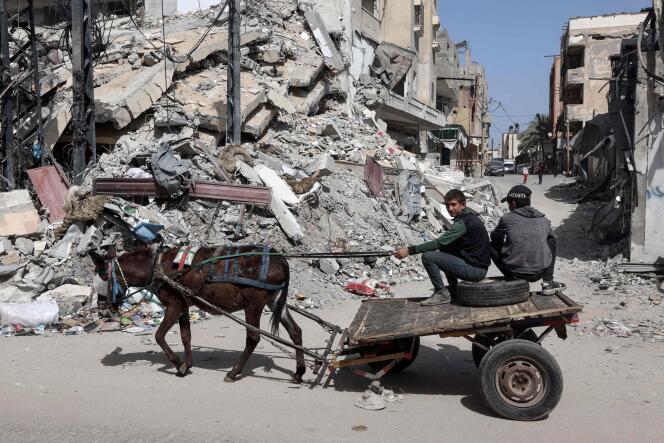 Palestinians on a donkey cart near a building destroyed by Israeli bombardment in Rafah, southern Gaza Strip, March 31, 2024.