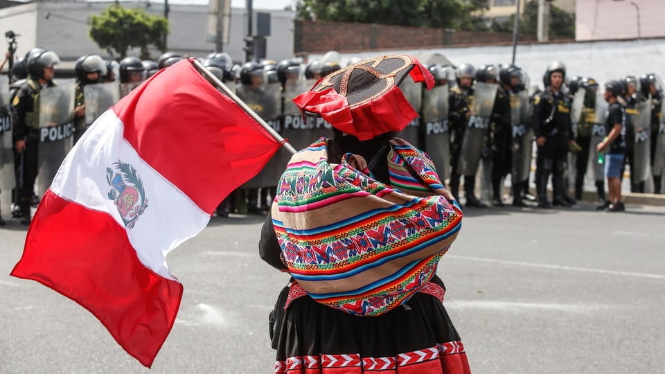 An indigenous woman carries the Peruvian flag during Dina Boluarte 2023 protests in Lima.