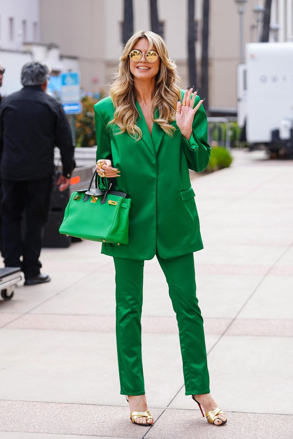 Heidi Klum wears a green pants suit, which she completes with a green Birkin bag and gold heels. 